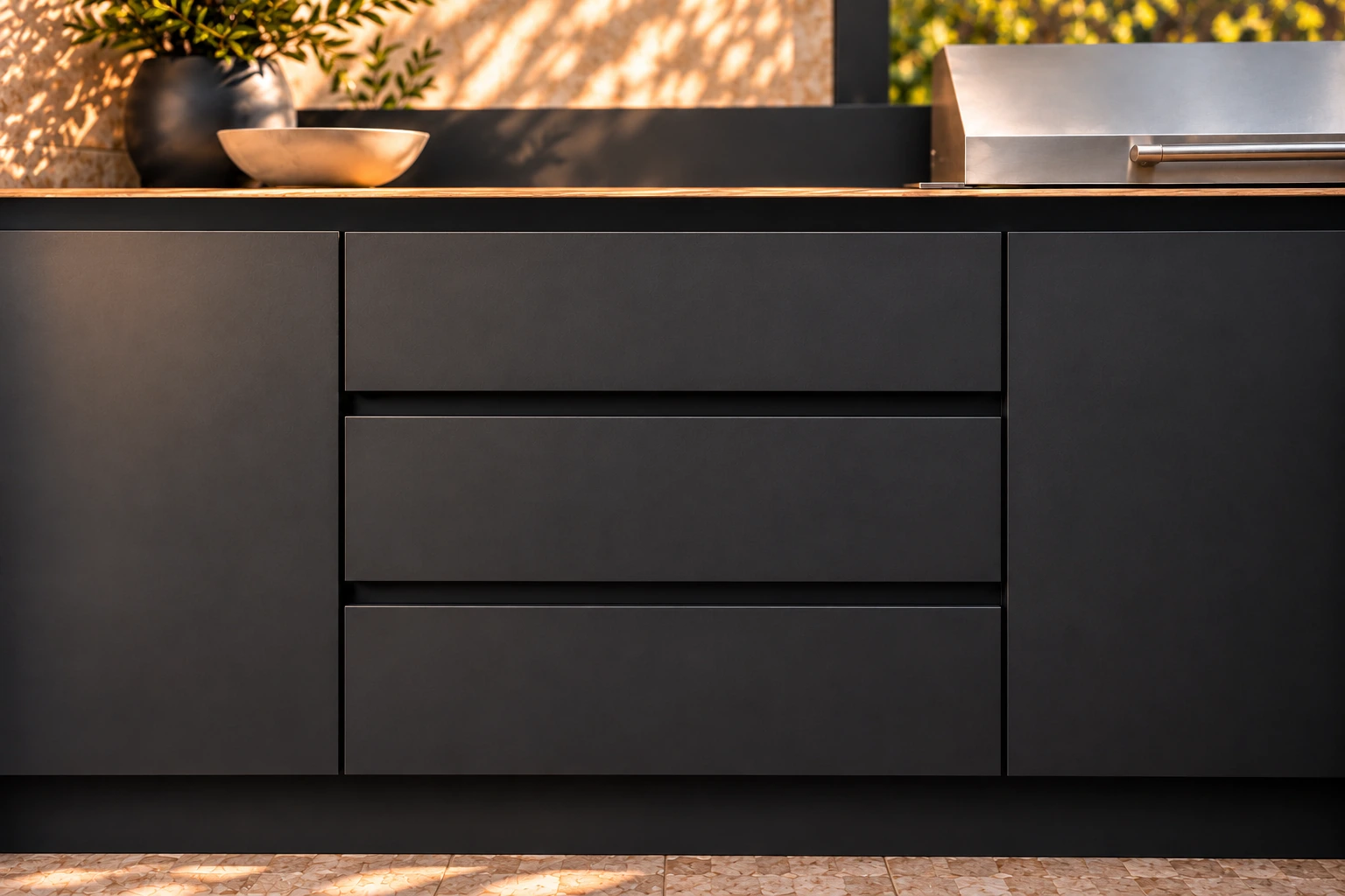 Three equal black drawer fronts with recessed finger pulls beneath an oak-look benchtop.